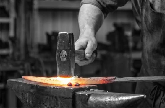 Craftsperson forging a blade